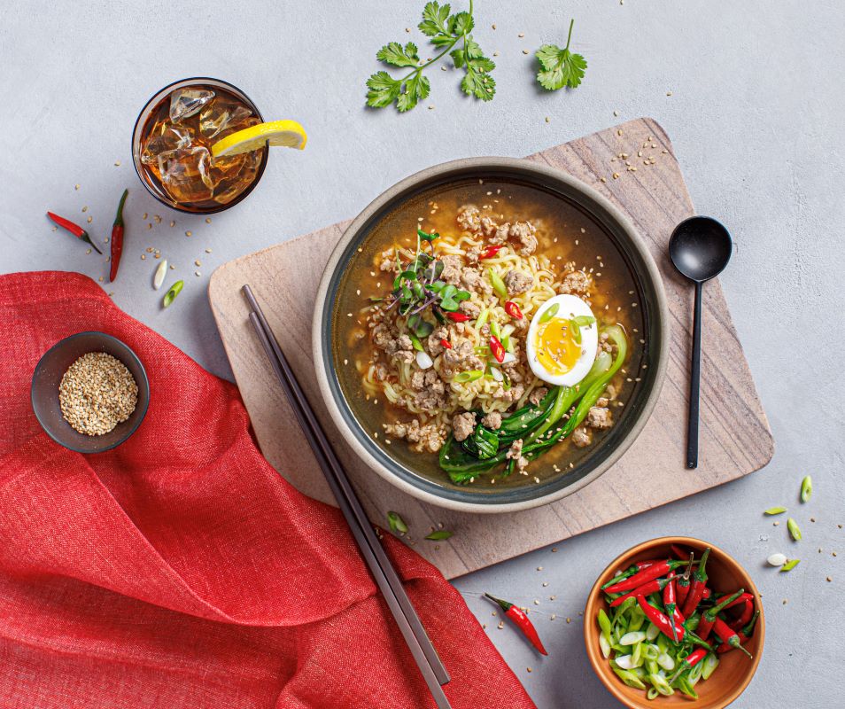 Miso ramen bowl with spicy Prairie Fresh® minced pork shoulder, egg, bok choy, green onions, red Thai chiles and sesame seeds.